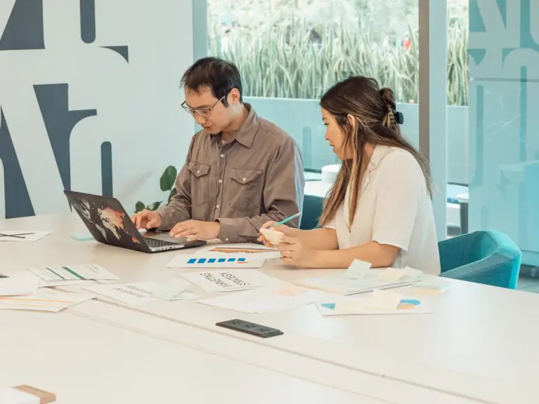 Twee collega's bespreken het plan achter een laptop